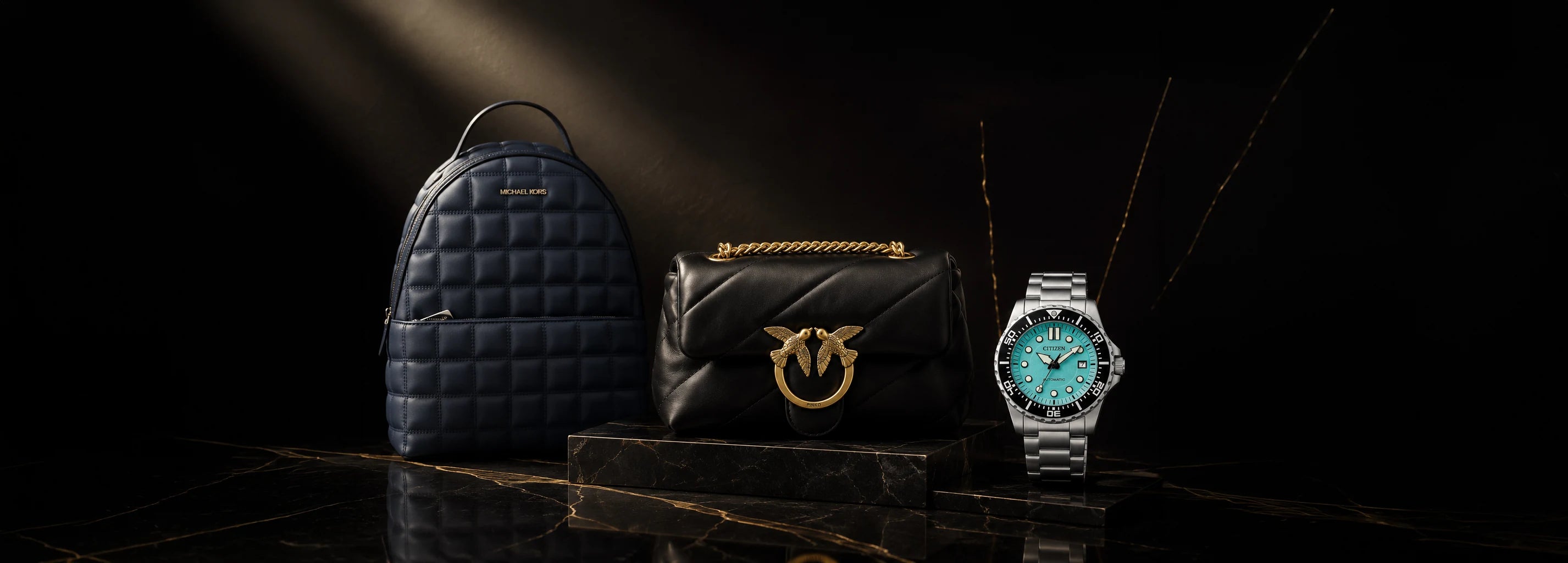 Quilted backpack, leather chain bag and silver dive watch on a dark marble plinth